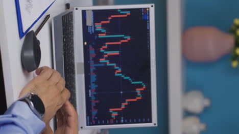 Vertical-video-of-Man-examining-and-thinking-financial-chart.
